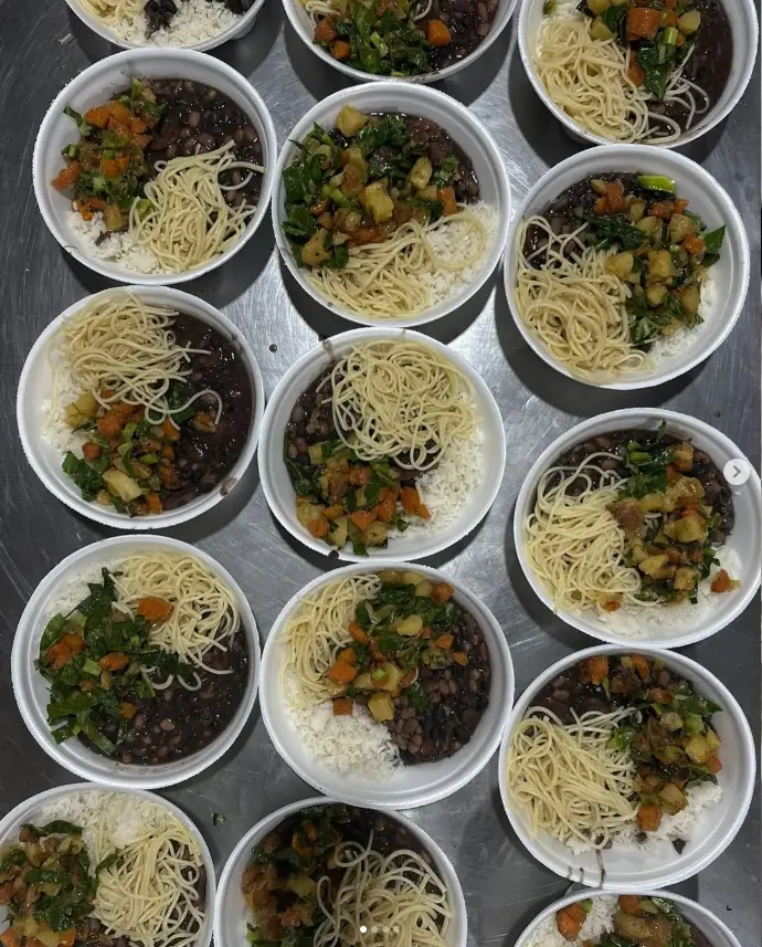 Várias marmitas de arroz, feijão, macarrão e legumes prontas para distribuição