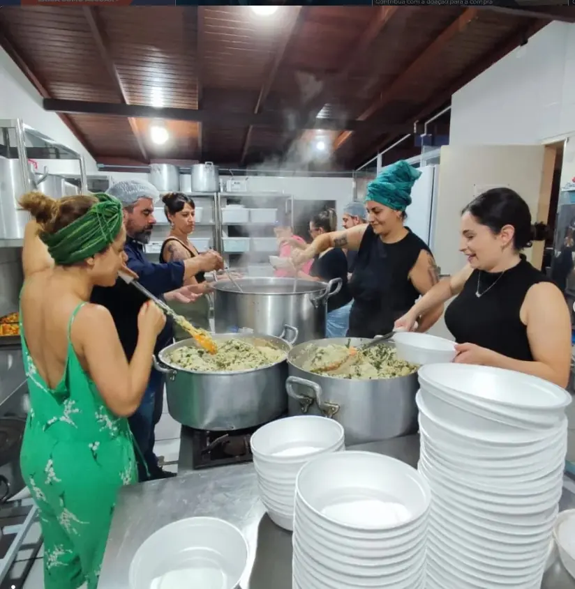 Voluntários preparando e servindo comida em uma cozinha comunitária